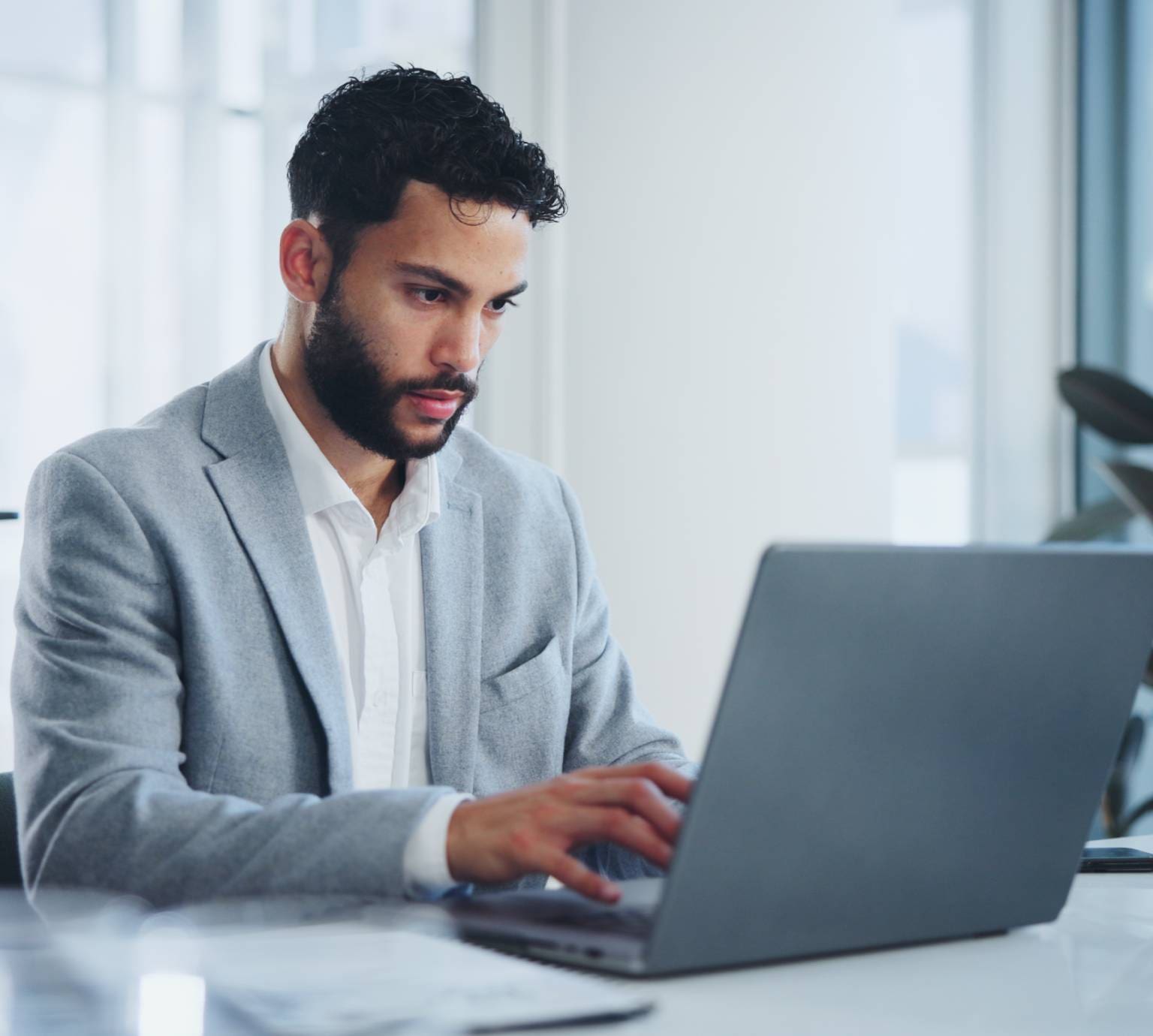 A man in a suit is using his laptop