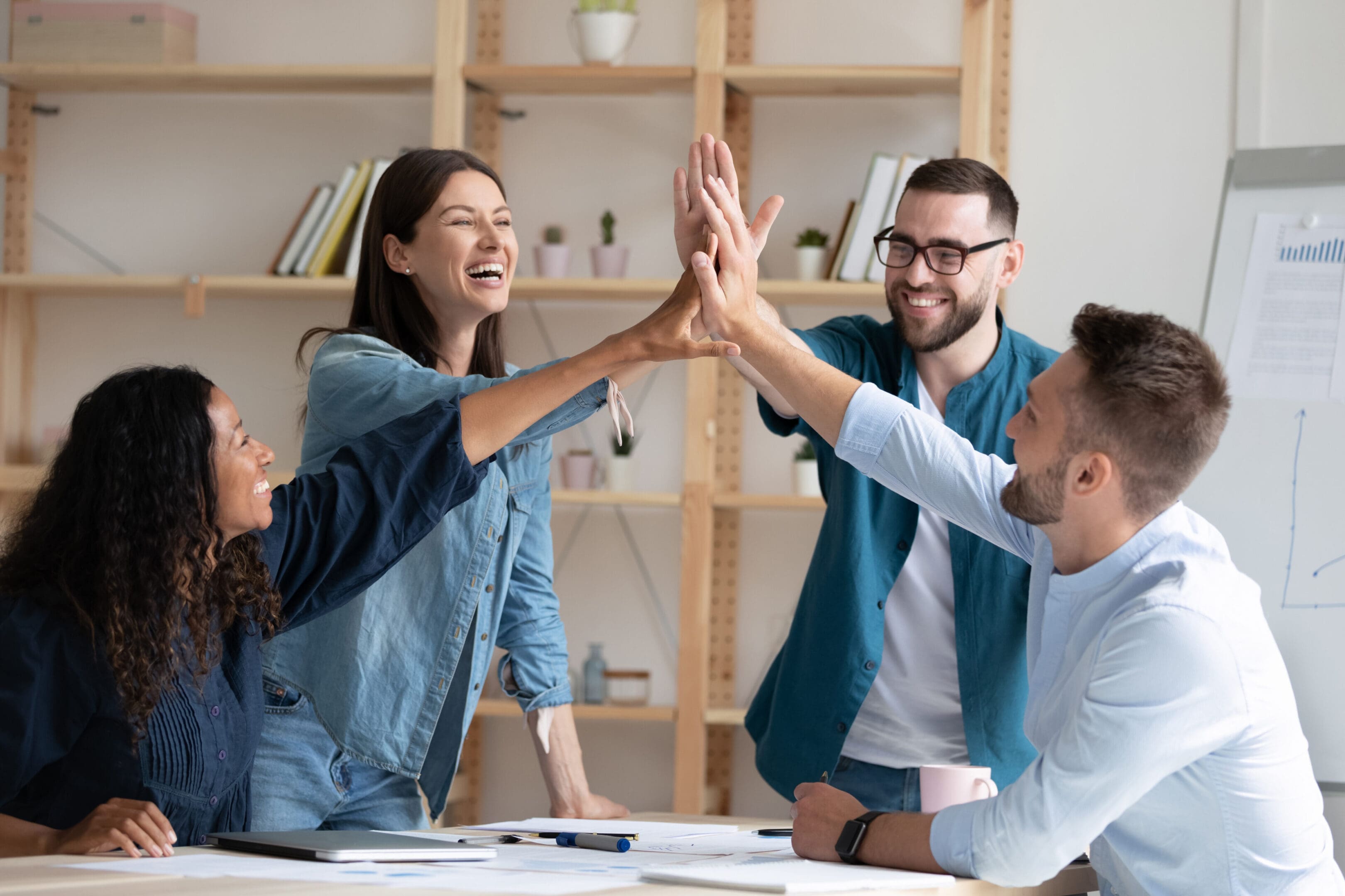 A group of people sitting at a table with their hands in the air.