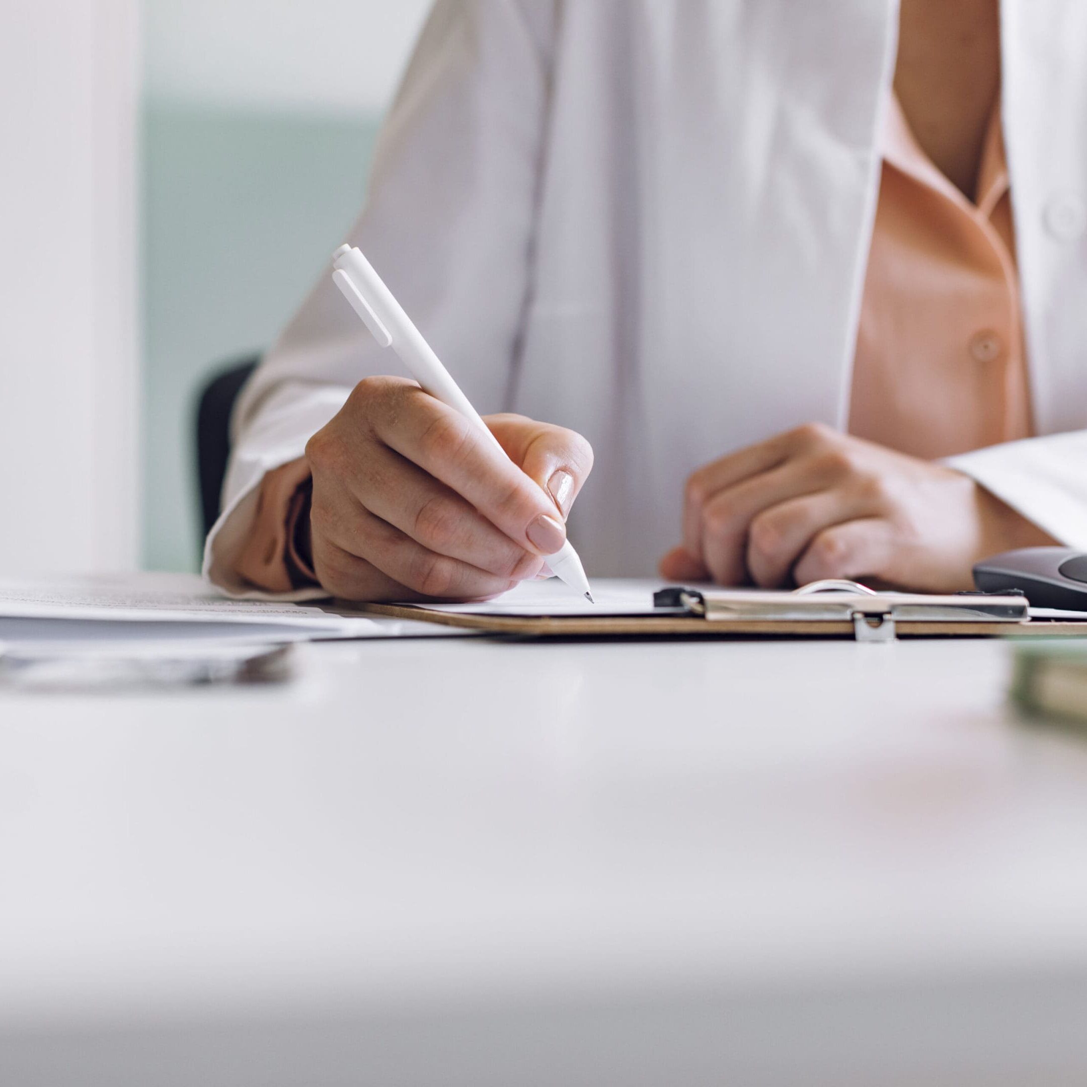 A person writing on paper with a pen.